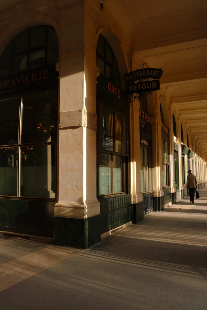 Sunlit corridor of Paris' Palais Royal highlighting classic architecture.
